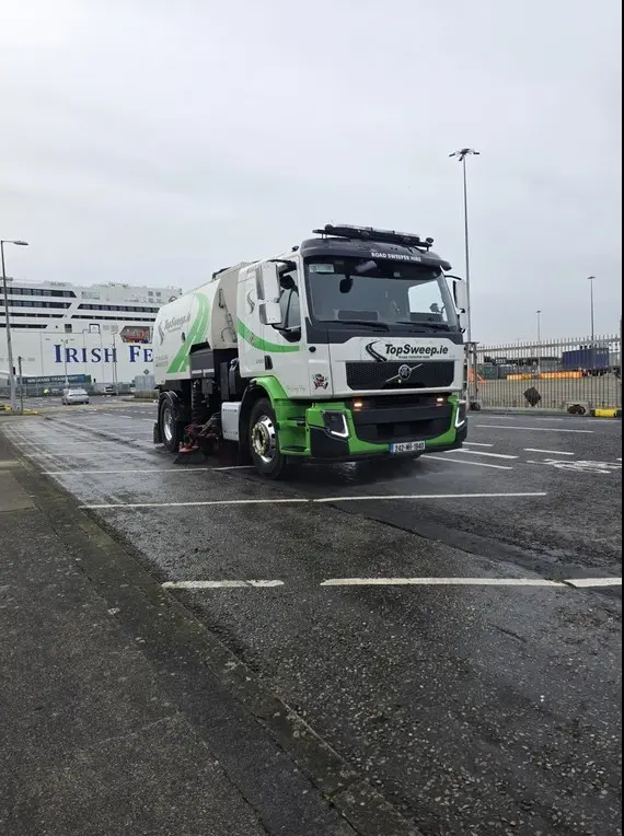 Top Sweep high-pressure power jet washer truck providing road cleaning services at Dublin Port with a large Irish Ferries ship in the background