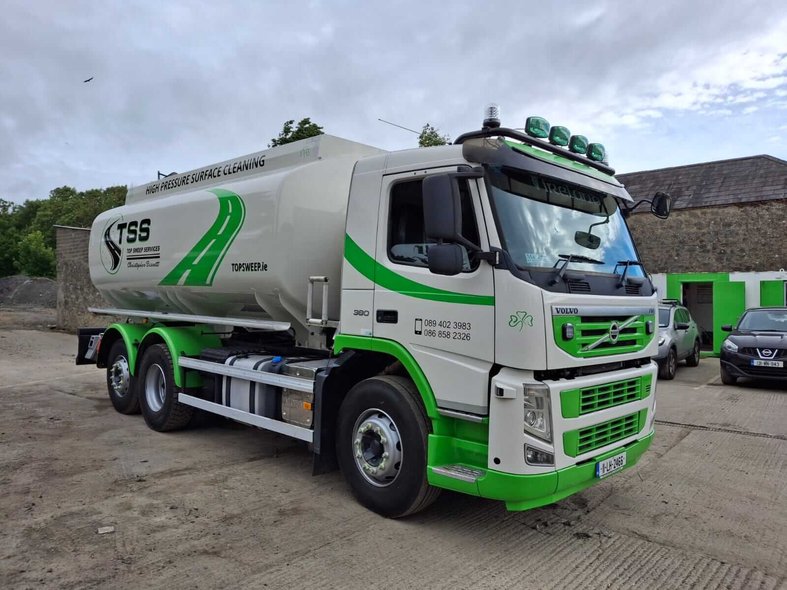 Top Sweep high-pressure surface cleaning jet washer truck removing construction debris and mud from a residential estate road